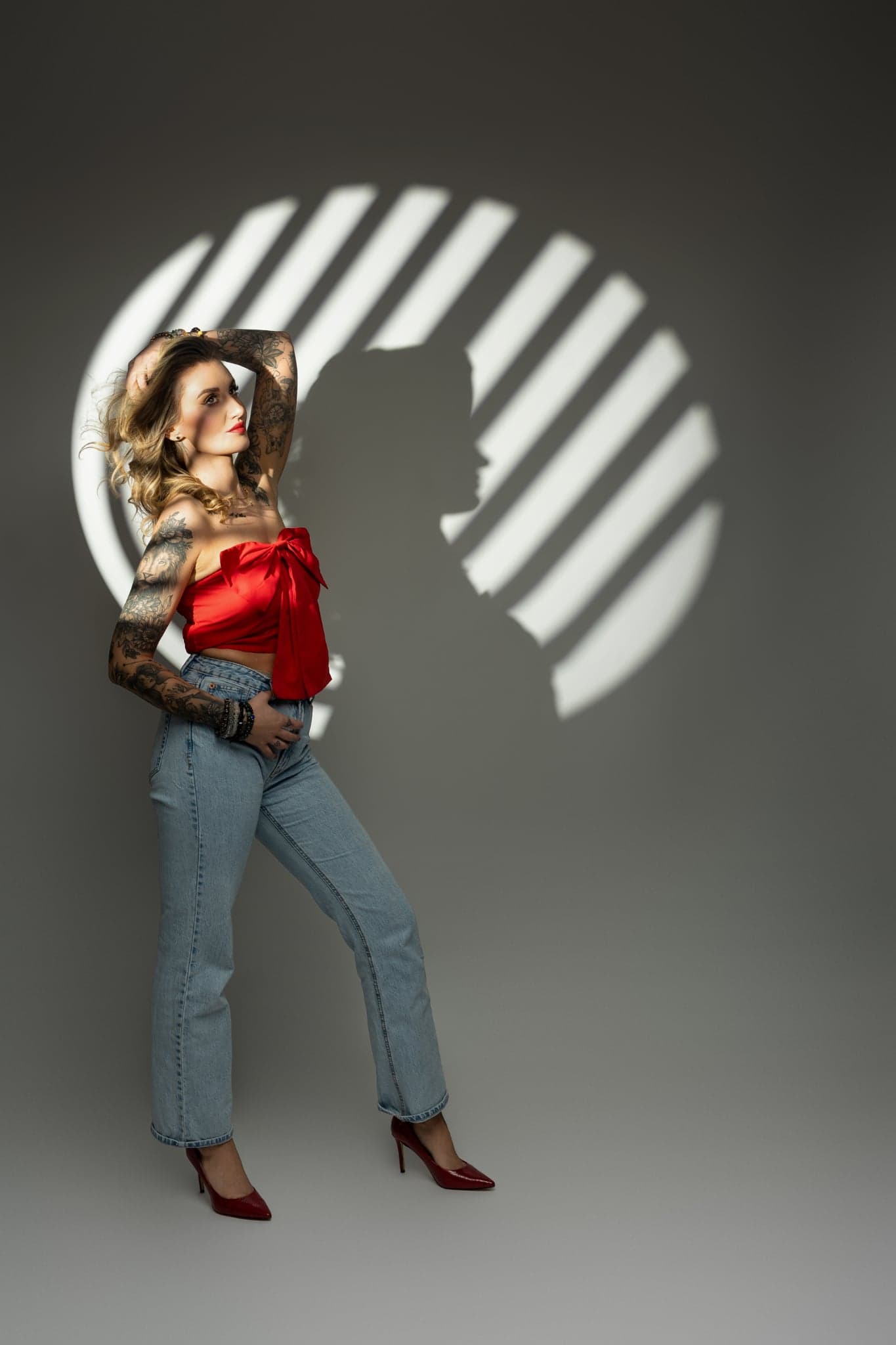 Karolina Gosz standing in a studio fashion portrait with red bow styling, confident posture and graphic contrast
